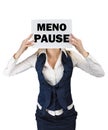 A woman in a suit standing holding a piece of paper with the word menopause at the level of the face