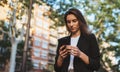 Woman in suit walking outdoor park and hold in hand mobile phone chatting with friends, successful businesswoman typing on touch Royalty Free Stock Photo