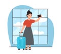 Woman with a suitcase at the airport takes a selfie on the phone. Goes on a flight to go on a trip.