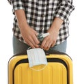 Woman with suitcase, antiseptic spray and protective mask on white background. Travelling during coronavirus pandemic