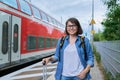 Woman with suitcase backpack on outdoor platform of railway station