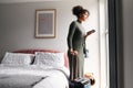 Woman With Suitcase Checking Out Of Boutique Hotel Waiting For Taxi Ordered On Mobile Phone App Royalty Free Stock Photo