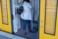 A woman with a suitcase gets on the train.