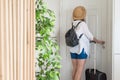 Woman with suitcase and straw hat in shirt and shorts going to the door and waiting a taxi. ready to trip. Individual traveler Royalty Free Stock Photo