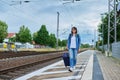 Woman with suitcase walking on outdoor platform of railway station