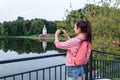 Woman in summer in city near lake, river and pond, photographing landscape on a smartphone, recording video on Internet Royalty Free Stock Photo