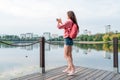 Woman summer city near lake, river pond, photographing landscape smartphone, recording video to Internet, application Royalty Free Stock Photo