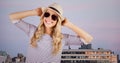 Woman in summer clothes with hands on head against buildings and evening sky Royalty Free Stock Photo