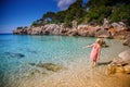 A woman in a summer dress and straw hat enjoying a stroll in the water along Cala Gat beach in Mallorca