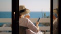 Woman with wine glass using cell when relaxing at the balcony overlooking sea Royalty Free Stock Photo