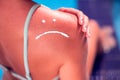 Woman with sun protection cream on her burned skin in the shape of sad smile. Summer, healthcare and vacation concept Royalty Free Stock Photo