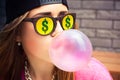 Woman in sunglasses with dollar makes a chewing gum bubble Royalty Free Stock Photo