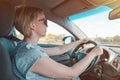 Woman in sunglasses drives modern car and drives on highway. Driver girl sits behind steering wheel of vehicle and looks at road