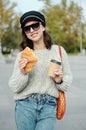 Portrait of a woman in sunglasses holding a string bag and paper cup of coffee Royalty Free Stock Photo