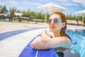 Woman looks out of the pool, hanging on the railing. Royalty Free Stock Photo