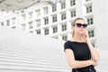 Woman in sunglasses posing on stairs and building in France