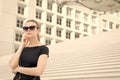 Woman in sunglasses posing on stairs and building in France