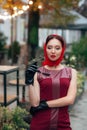 Woman with sunglasses, in a red dress, leather gloves, tights, red shoes and a scarf, stands on the street Royalty Free Stock Photo