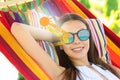 Woman with sunglasses resting in hammock outdoors. UVA and UVB rays reflected by lenses, illustration