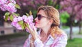 Woman in sunglasses smelling cherry tree blossom profile view Royalty Free Stock Photo