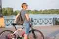 Woman in sunglasses stands with a bicycle on the promenade in th Royalty Free Stock Photo