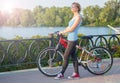 Woman in sunglasses stands with a bicycle on the promenade in th Royalty Free Stock Photo