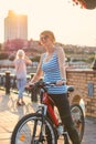 Woman in sunglasses stands with a bicycle on the promenade in th Royalty Free Stock Photo