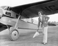 Woman in sunglasses waving a flag on the tarmac next to a airplane