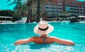 Woman with sunhat relaxing in swimming pool at spa resort. Royalty Free Stock Photo