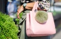 Woman on a sunny day in summer or spring with a big bag. Bag pink with keying bubo. Fashionable bag close-up in female hands. Royalty Free Stock Photo