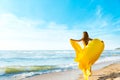 Woman on Sunny Sea Beach in Yellow Fluttering Dress, Fashion Model Back Rear View, Silk Cloth Waving on Wind Royalty Free Stock Photo