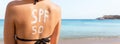 Woman with sunscreen in form of SPF 50 word on her back sunbathing at the beach. Sun protection factor concept Royalty Free Stock Photo