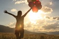 Woman on sunset grassland with colored balloons