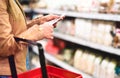 Woman in supermarket aisle with food shelf reading shopping list Royalty Free Stock Photo