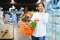 Woman in supermarket. Beautiful young woman talking on mobile phone and smiling while standing in a food store Royalty Free Stock Photo