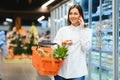 Woman in supermarket. Beautiful young woman talking on mobile phone and smiling while standing in a food store Royalty Free Stock Photo