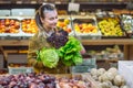 Woman in the supermarket. Beautiful young woman shopping in a supermarket and buying fresh organic vegetables