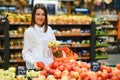 Woman in a supermarket at the vegetable shelf shopping for groceries, she is choosing Royalty Free Stock Photo