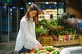 Woman in a supermarket at the vegetable shelf shopping for groceries, she is choosing Royalty Free Stock Photo