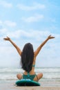 Woman surfer in bikini sitting on surfboard on beach in front of sea Royalty Free Stock Photo