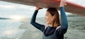 Woman, surfer with surfboard at beach and view of ocean, nature and extreme sports for fitness. Asian, athlete and smile Royalty Free Stock Photo