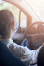 Woman in surgical face mask and gloves driving car