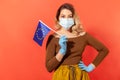 Woman in surgical face mask and gloves holding European Union flag, concept of coronavirus pandemic threat Royalty Free Stock Photo