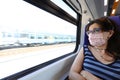 Woman with surgical mask travel by train during the Emergency of