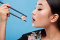 Asian woman with sushi eating sushi and rolls on a blue background Royalty Free Stock Photo