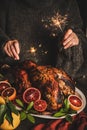 Woman in sweater burning sparkles over Christmas whole roasted turkey