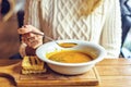 Woman in sweater eating dry pea soup on wooden platter Royalty Free Stock Photo