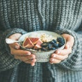 Woman in sweater holding bowl of rice porridge, square crop Royalty Free Stock Photo