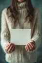 A woman in a sweater holding up an empty piece of paper, AI