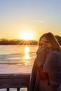 Woman in sweater standing on bridge by frozen lake at sunset Royalty Free Stock Photo